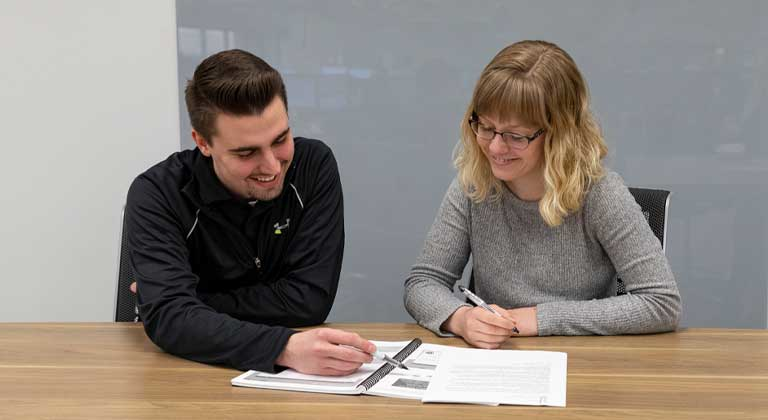 Two sentry employees looking at a binder