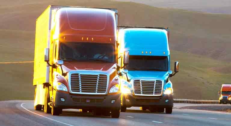 Two trailer trucks driving down highway