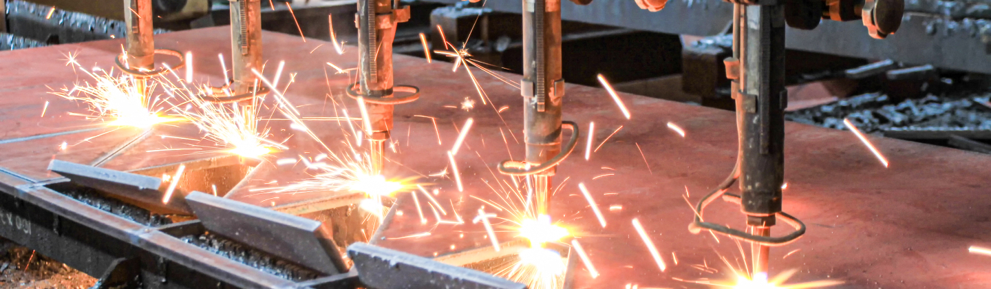 Multiple cutting torches cutting metal with sparks flying.
