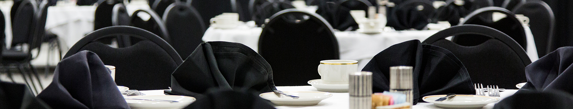 Tables set with cutlery and black napkins in the fieldhouse