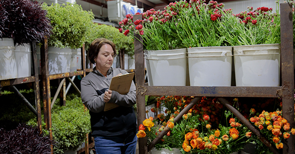 woman with clipboard next to flowers