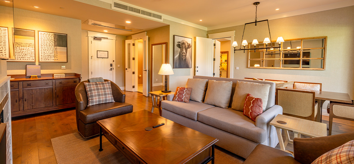 carousel-suite-golf-view-king-queen-8-1200x556 Suite parlor room with a dining room table and seating area.