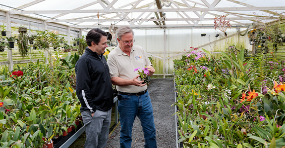 two men in a greenhouse discussing flowers