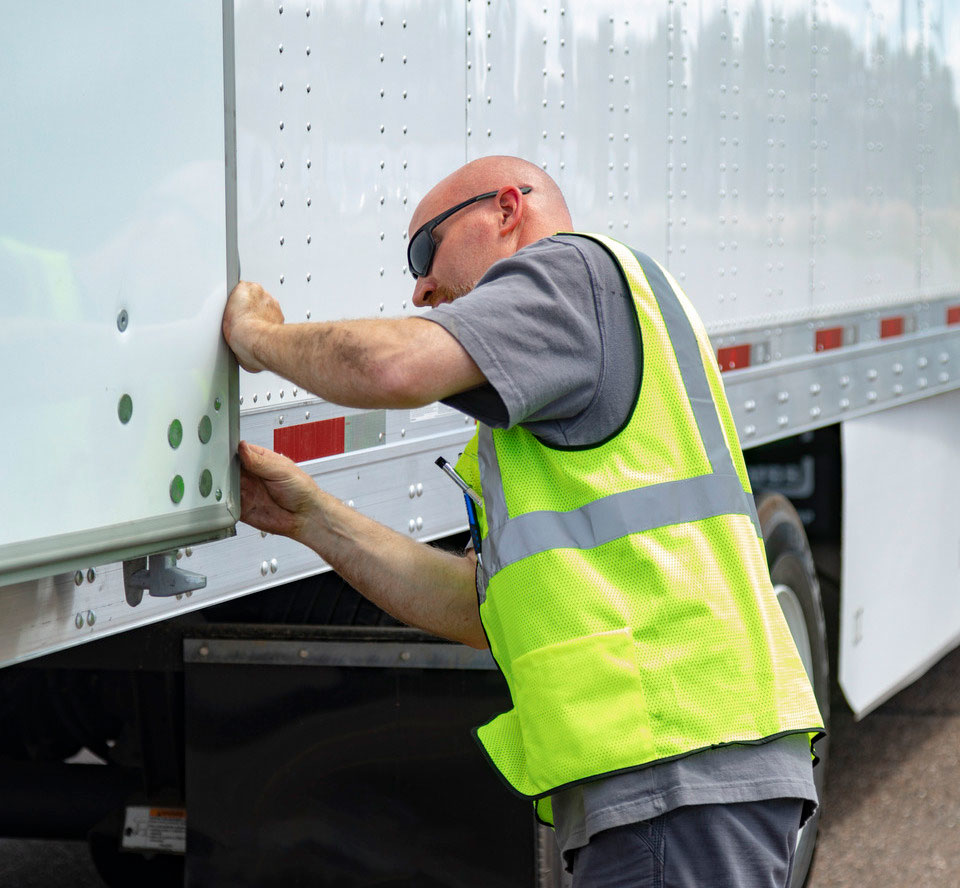 Driver in a safety vest checking out his truck.