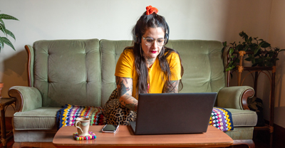 Woman working on laptop while sitting on couch