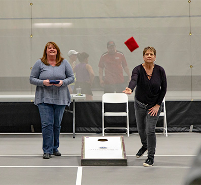 Women playing bean bag toss in the SentryWorld fieldhouse