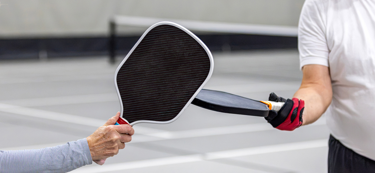Pickleball players touch paddles.