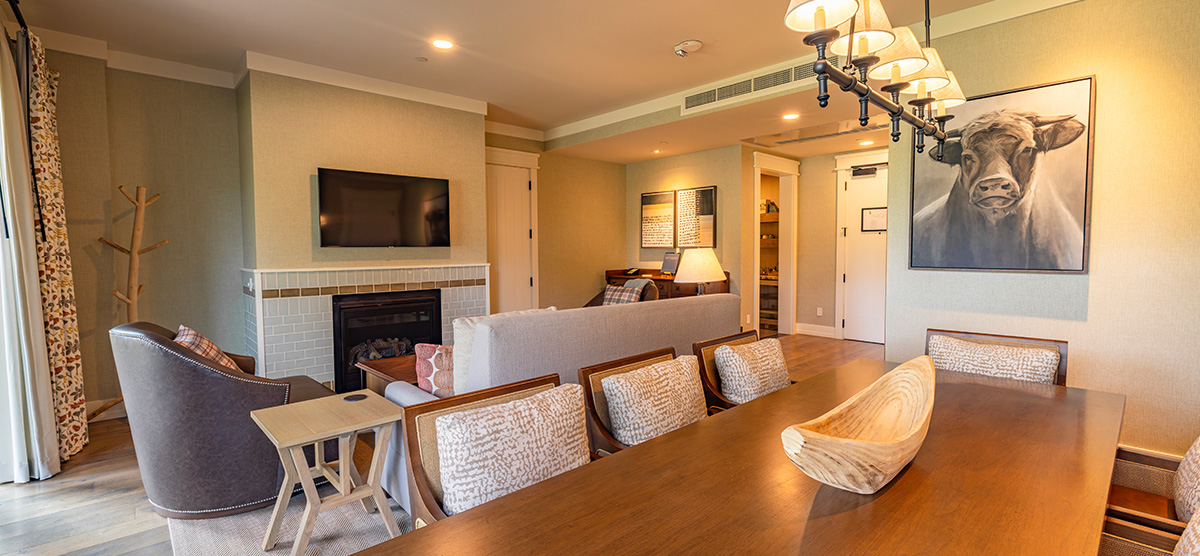 carousel-executive-king-suite-2br-1-1200x556 Executive suite parlor area with dining room table and seating area.