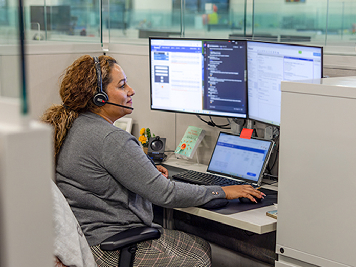 teams-customer-service-woman-headset-computer-696x522 Woman speaking to a customerwith a headset