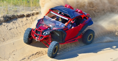Red ATV driving on a sandy trail.