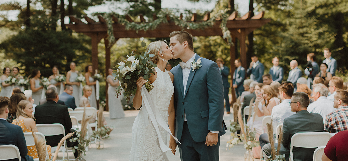 Bride and groom kissing at the end of an aisle after their wedding