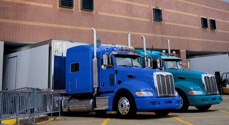 Two blue semi trailer trucks in dock area