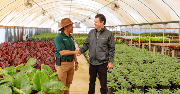 two men shaking hands in a greenhouse