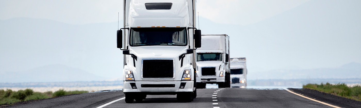 White semi trailer trucks driving down highway