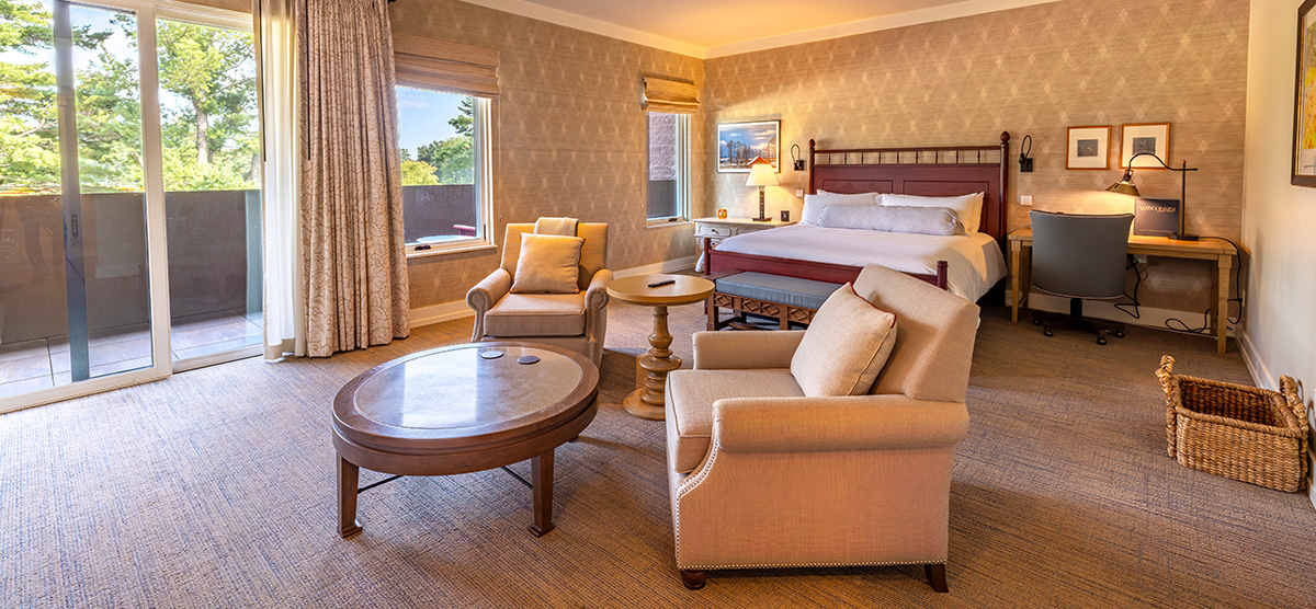 carousel-accessible-golf-view-executive-junior-suite-1-1200x556 King bed with two chairs, coffee table and a desk.