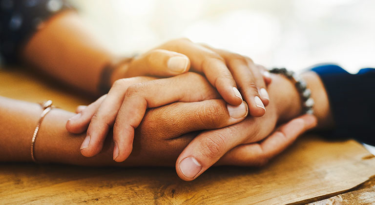 Close up of two people's hands holding one another