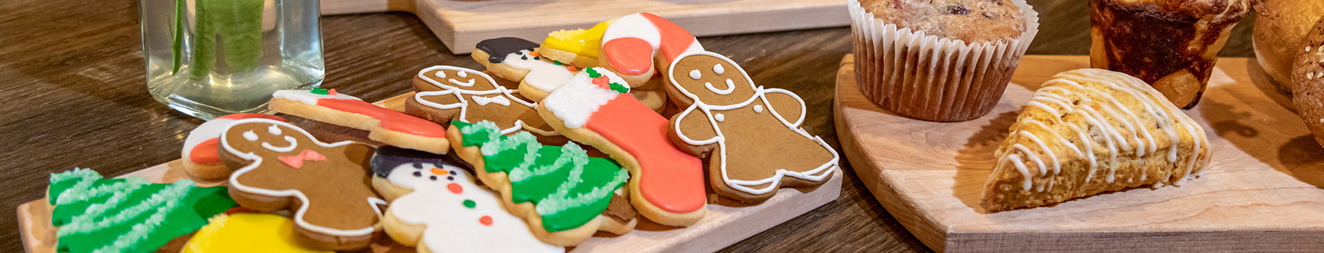 Holiday cookies on a wooden tray next to other bakery items