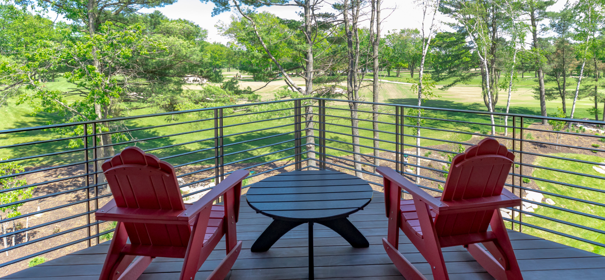 Deck overlooking hole 18 with two red Adirondack chairs. 