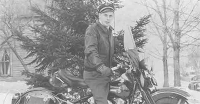 Black and white photo of a man on a motorcycle in winter