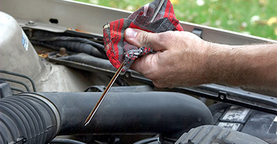 Close up of a man checking the oil with a dip stick