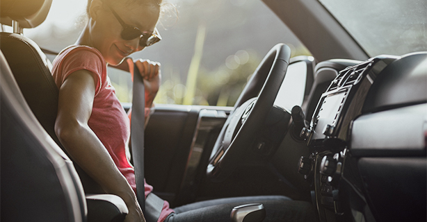 Woman driver buckling up the seat belt before driving car