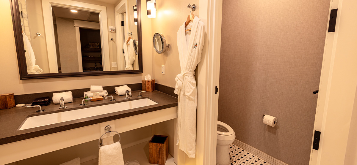 carousel-executive-queen-terrace-3-1200x556 Bathroom with large sink and bathrobe.