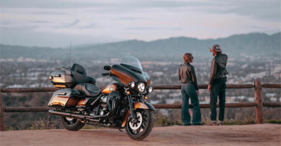 Two people talking near a motorcycle at a scenic overlook.