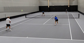 People playing doubles co-ed tennis in the SentryWorld fieldhouse