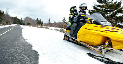 Two snowmobile riders on a snowy road