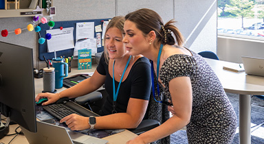 Two women looking at a computer and working together at a Sentry office