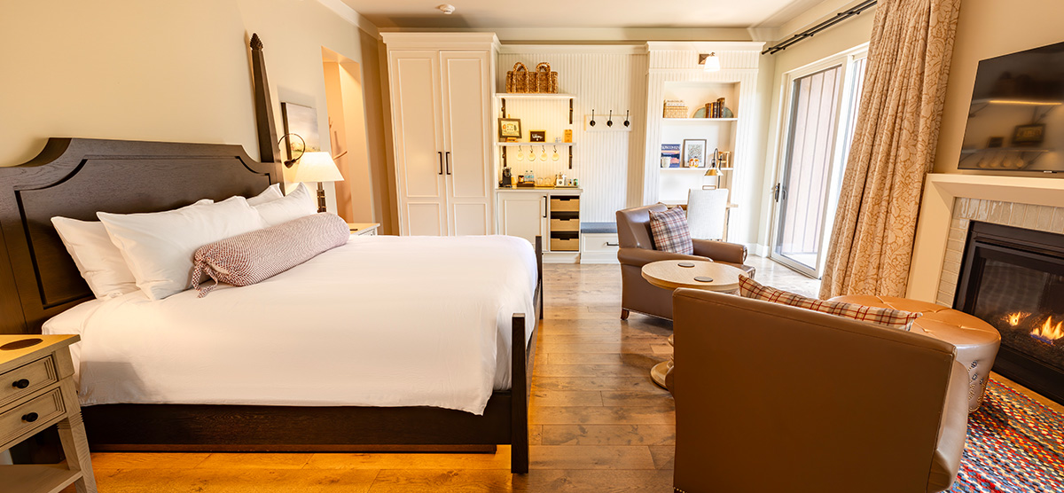 carousel-golf-view-executive-level-luxury-junior-suite-1-1200x556 Room with a king sized bed and two chair seating area with fireplace.