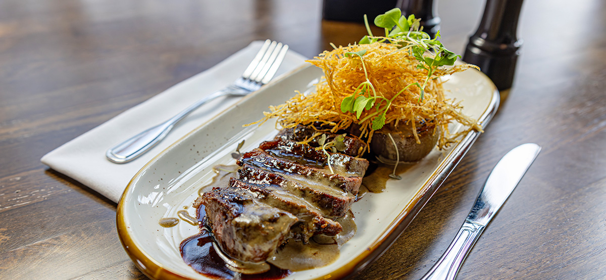 Top Sirloin with porcini mushroom cream, confit cippolini onion, potato strings, and red wine reduction.