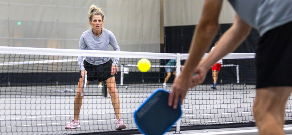 Pickleball players dinking across the net.