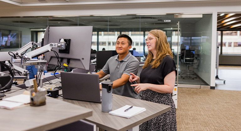 man and woman working together on a computer in an office setting
