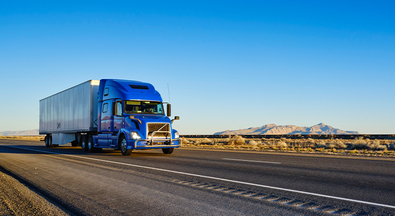 semi truck driving on highway with mountains in background