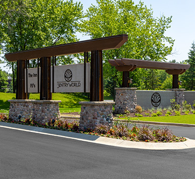 Entrance sign for SentryWorld with stone pillars and wooden beams.