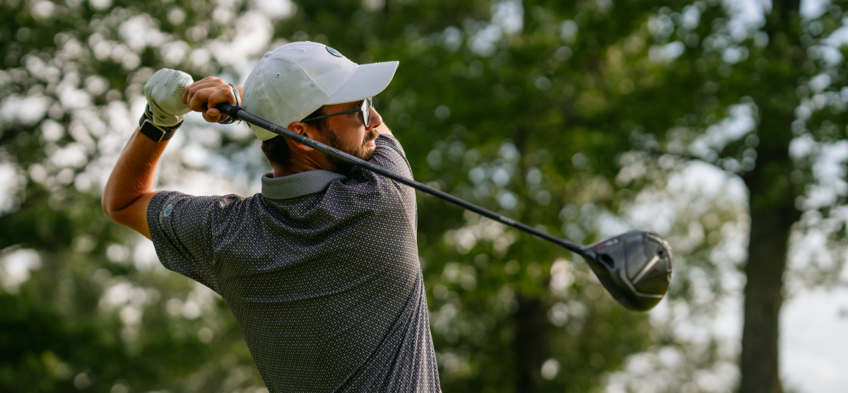 Male golfer at the end of his swing using his driver. 