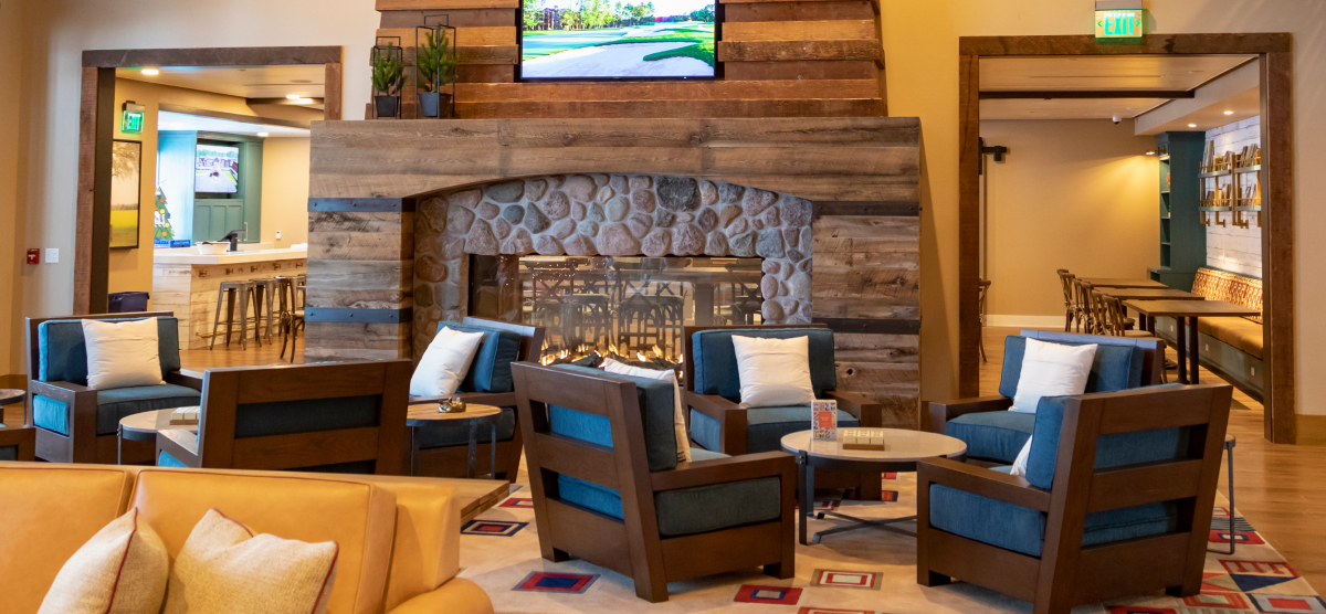 Large chairs in front of a fireplace with two entrances on either side to the Library Cafe. 