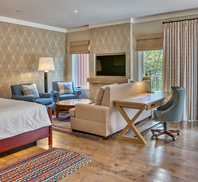 image-card-rooms-suites-396x364 A suite at The Inn sitting area in front of a TV and fireplace.