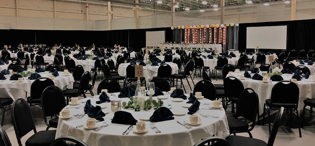 carousel-wedding-venue-fieldhouse-6-1200x556 Many round tables with chairs set up for a wedding reception in the fieldhouse.