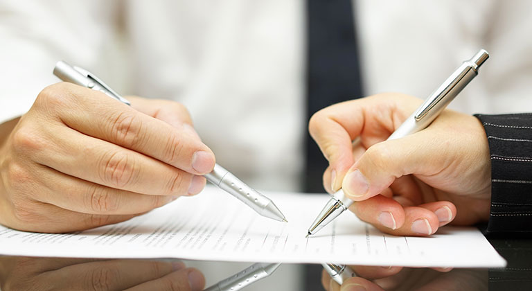 Two people with pens reviewing document