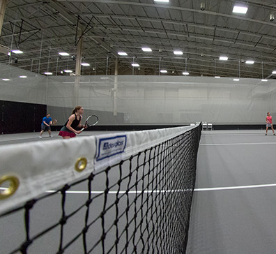 Tennis net and players on a court in the SentryWorld fieldhouse