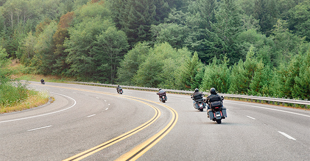 Several motorcycle riding along a two-lane highway