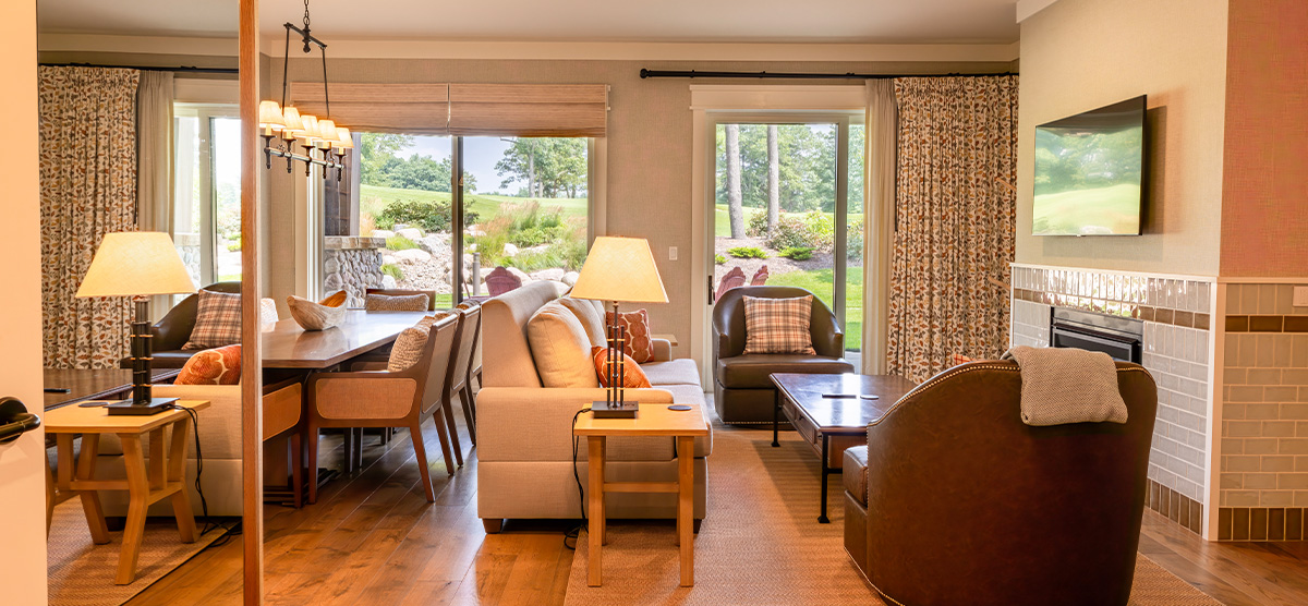 carousel-suite-golf-view-queen-4-1200x556 Suite parlor room with dining room table and sitting area.