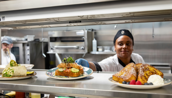 50-50-chef-mercedes-breakfast-597x339 Chef in a kitchen presenting a wrap, sandwich, and French toast.