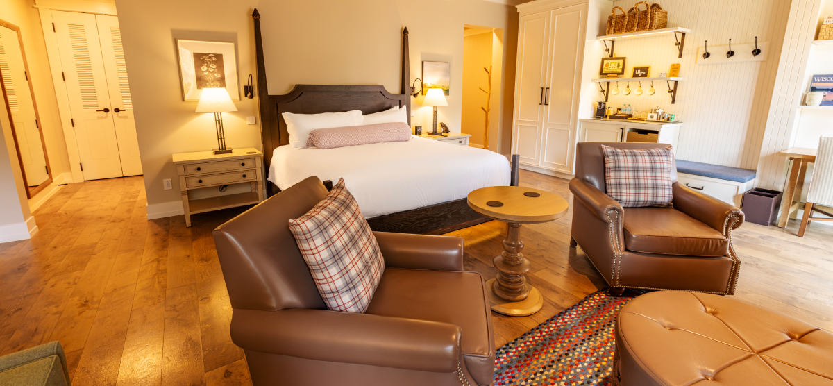 Two leather chairs in front of a king size bed. 