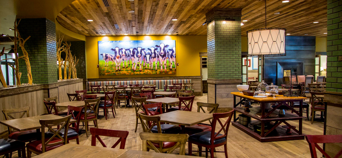 PJ's restaurant seating with large cow painting in background.