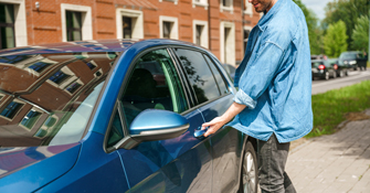 Man holding on to a door handle of his car