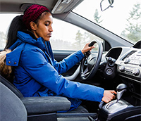 Woman setting the parking brake in her car