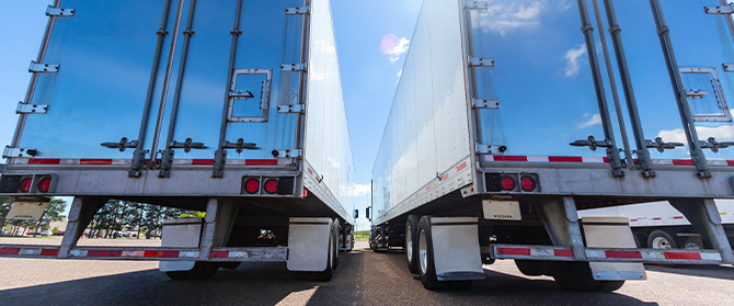 The back end of two large semi-trucks parked next to one another